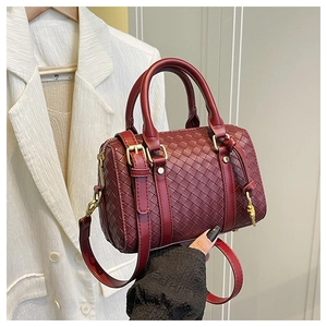 Detail of dark burgundy woven handbag showing leather texture and gold-tone metal hardware
