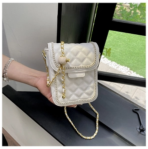 Gros plan sur le cuir matelassé blanc et la bandoulière dorée d'un petit sac carré
