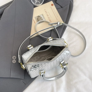 Detailed top view of silver woven mini boston bag on blazer with cafe props