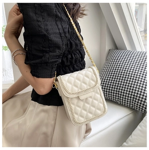Détail du sac de téléphone blanc matelassé avec élégante bandoulière et bordure en chaîne dorée