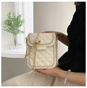 Détail du sac matelassé beige avec bordure en chaîne dorée et boule de réglage en métal