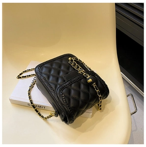 Détail du sac matelassé noir avec chaîne dorée posé sur une chaise minimaliste