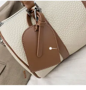 Detail of lychee pattern leather handbag with contrast brown edges and silver metal hardware