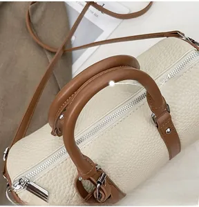 Detailed macro view of the cream lychee grain leather stitching and brown round handle