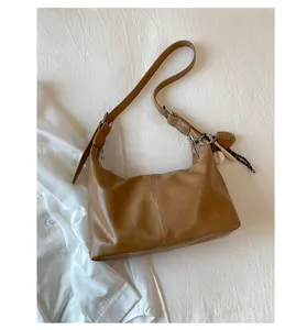 Detailed top view of a brown faux leather hobo bag with a sporty baseball charm