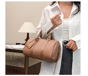 Close-up of brown pebbled leather bowling bag with dual handles and metal buckles
