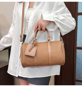 Detailed view of the brown lychee pattern leather Boston bag with a leather hangtag