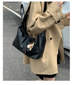 Fashionable black tote bag with matte leather texture and baseball charm accessory