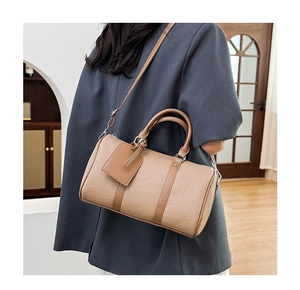 Detail of khaki pebbled leather Boston bag showing crossbody strap and texture on a model