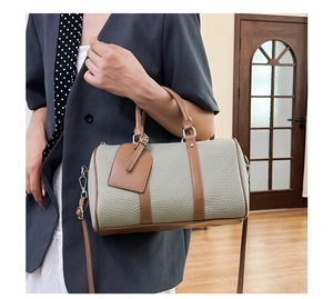 Detail of grey-green litchi grain leather bowling bag with brown straps and silver hardware