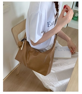 Detailed side view of a large brown leather hobo bag with unique decorative charms