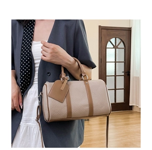 Detail of beige pebble leather Boston bag with brown trim and adjustable shoulder strap