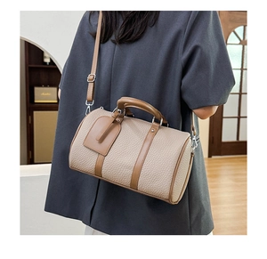 Detail of beige contrast bowling bag with pebbled leather texture and silver hardware