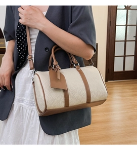 Chic cream and brown bowling bag worn by a model in an elegant professional outfit