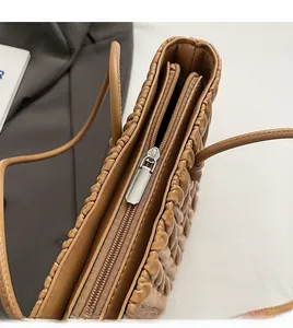 Détail de la fermeture éclair et texture du cuir matelassé sur un cabas marron