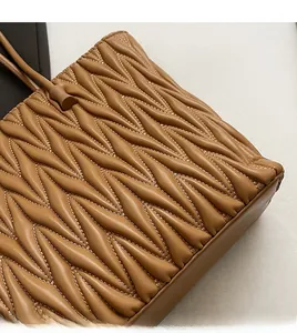 Gros plan sur la texture en cuir matelassé marron et les coutures de ce sac cabas
