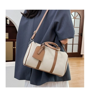 Detail of cream lychee leather bowling bag with brown handles on a model shoulder