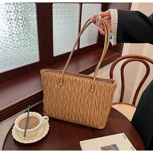 Détail du sac cabas matelassé camel avec texture plissée sur un rebord de fenêtre