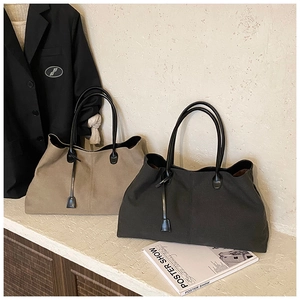 Detail of khaki and grey canvas tote bags with long black straps on a textured surface
