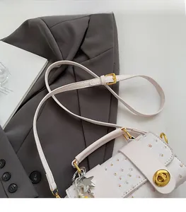 Detail of white mini pillow bag featuring gold swivel lock and adjustable shoulder strap