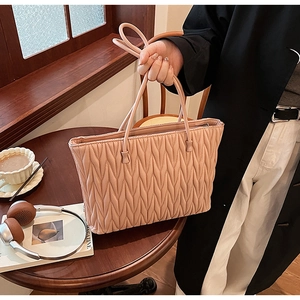 Sac fourre-tout matelassé rose avec texture froncée dans un décor de café
