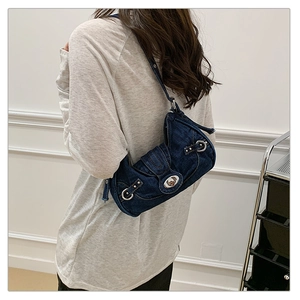 Detail of dark blue denim underarm bag with silver buckle and Y2K vintage rivets