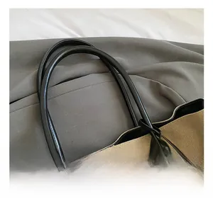 Close-up of black leather handles and beige canvas material on a vintage tote bag