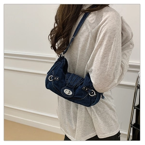 Side view of a vintage dark blue denim underarm bag worn on a model against white wall