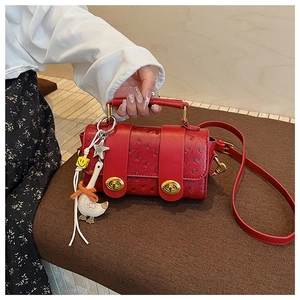 Close-up of red ostrich pattern handbag with golden twist locks and cute duck pendant