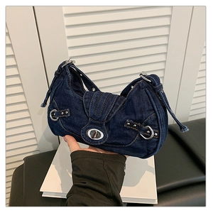 Detail of dark blue denim underarm bag featuring silver metal twist lock and Y2K rivets