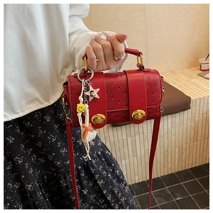 Detail of red ostrich pattern texture and golden twist locks on the crossbody bag