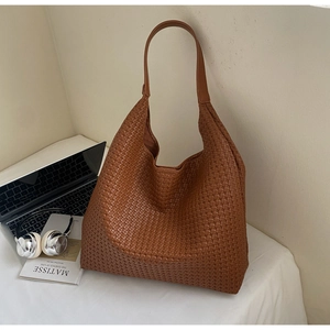 Brown woven hobo tote bag styled with a laptop and book in a minimalist workspace