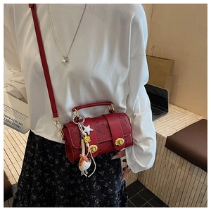 Detail of red ostrich texture mini crossbody bag with gold clasps and cute charms