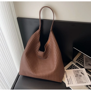Close-up of brown woven leather texture on a large capacity tote bag with long strap