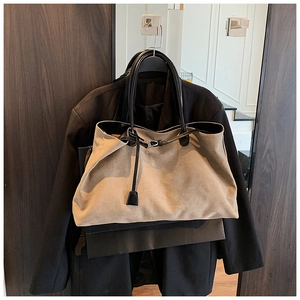 Close-up of matte suede tote bag with black shoulder straps and minimalist metal buckle