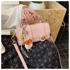 Pink ostrich pattern handbag detail with golden hardware and cute goose plush charm