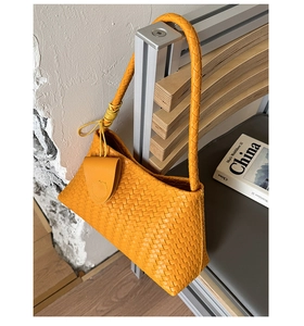Close-up of bright yellow woven shoulder bag with intricate cross-weave texture and detail