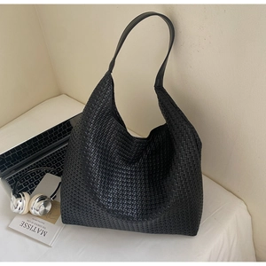 Detail of black woven tote bag with a modern lifestyle setting including headphones