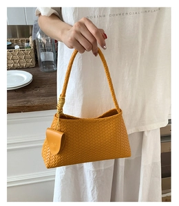 Detailed view of yellow woven shoulder bag with matching round coin purse and textured strap