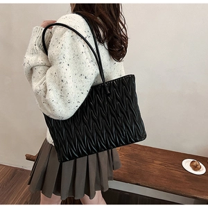 Vue latérale d'un grand sac cabas plissé noir porté à l'épaule par un mannequin