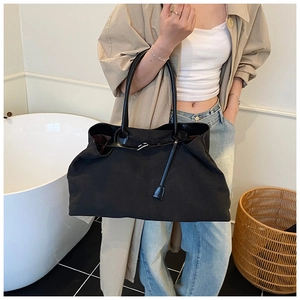 Minimalist black canvas tote bag styled as an underarm shoulder bag on a model