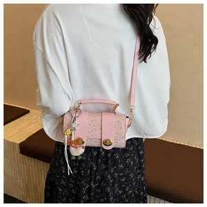Detail of pink ostrich texture bag with gold hardware and duck charm on a model