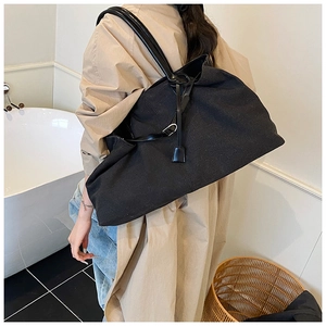 Detail of black canvas tote bag showing leather straps and drawstring closure