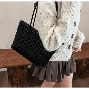 Sac cabas matelassé noir à texture ondulée porté à l'épaule pour un look élégant