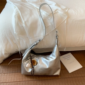 Silver metallic hobo bag with baseball charms on a minimalist background