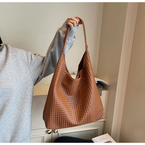 Close-up of caramel woven tote bag showing premium texture and hobo style on a model