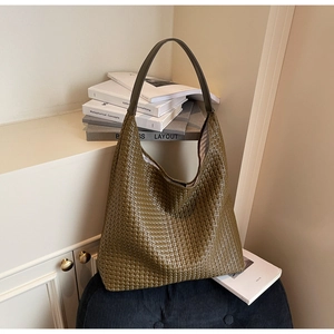 Detail of olive green woven leather hobo bag on a stool in a minimalist home setting
