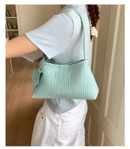 Close-up of mint green woven shoulder bag with intricate crisscross texture and mini pouch