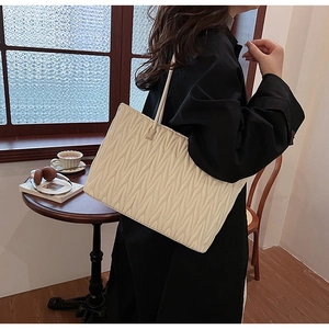Détail macro du sac cabas blanc crème avec une élégante texture matelassée en forme de V