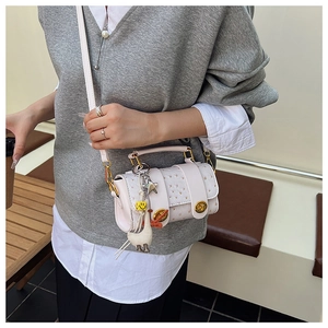 Detail of white ostrich-textured cylinder bag with charms and metal twist lock